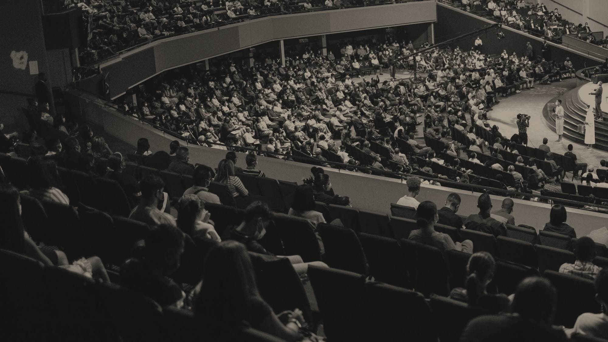 A full conference audience in a darkened auditorium